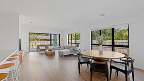 A spacious living area with a large round table, black chairs, a sofa, and a TV. - Saltline House - Point Lonsdale (Point Lonsdale)