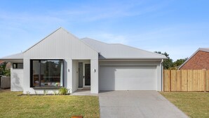 Et moderne hus i et plan med garage, stor skydedør og en velplejet græsplæne.