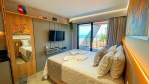 A hotel room with a bed, a TV, a balcony with a view, and a wooden cabinet.