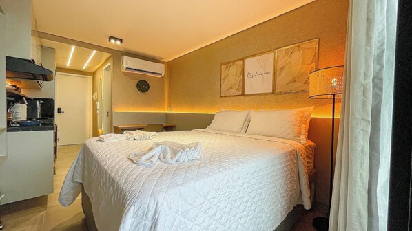 Une chambre d’hôtel équipée d’un lit, d’un bureau, d’une chaise, d’une horloge et d’un climatiseur fixé au mur.