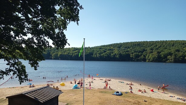 Ein Strand mit einer Holzkonstruktion, einem Fahrrad und einer Fahnenmasten.