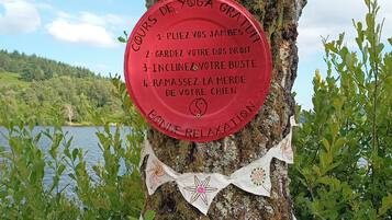 Un arbre auquel est fixée une pancarte rouge, entouré de verdure et avec un lac en arrière-plan.