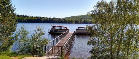 A wooden dock extending into a lake, surrounded by trees and a clear sky.