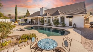 A house with a swimming pool, patio furniture, and a decorative table. - 4BR Home | Pool, Hot Tub, Game Room & Fire Pit (Mesa)