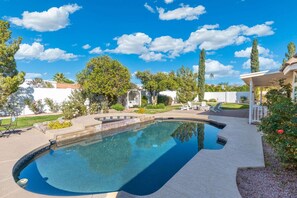 Une piscine au design incurvé, entourée d’un patio aménagé avec du mobilier d’extérieur.