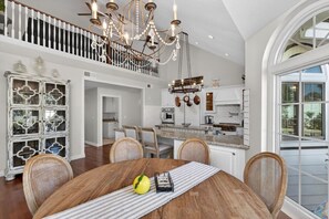 Un vaste espace dédié à la salle à manger, avec une table en bois, des chaises et un lustre.