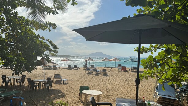 A beachside seating area with tables and chairs under umbrellas, overlooking the sea. - Double Room 300 at the Hotel Legendario (Sosúa)
