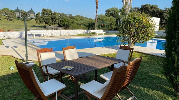 Ein Poolbereich mit Tisch und Stühlen, einem Pool und umgebender Bepflanzung.