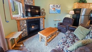 A cozy living room with a fireplace, a television, and a sofa.