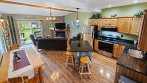 A modern kitchen with wooden cabinets, a central island, and a dining area with a table and chairs.