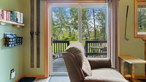 A cozy room with a sliding glass door leading to a deck, a comfortable sofa, and a bookshelf filled with books.