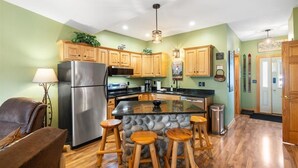 A modern kitchen with wooden cabinets, a stainless steel refrigerator, and a central island with stools.
