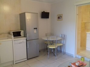 A compact kitchen with a refrigerator, microwave, and dishwasher. There is a small dining table with chairs. - Apartment 4 pers classé ***,proximité Calvi/Calenzana (CALENZANA)