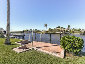 A waterfront property with a dock, grassy areas, and a clear view of the water.