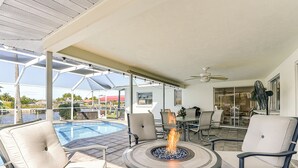 An outdoor patio with a fire pit, seating, and a view of a water body. - Sunset Reach ...Waterfront Family Pool Home - Gulf Access -  Sunset Views - (Cape Coral)