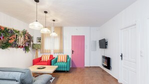 En stue med sofa, sofabord og et fjernsyn ophængt på væggen.
