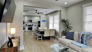 Uma sala de estar moderna com uma mesa de centro de vidro, um sofá e uma área de jantar com um banco.