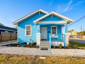 Une maison de plain-pied avec un porche à l’avant, une boîte aux lettres et un petit jardin.