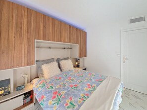 Une chambre à coucher avec une tête de lit en bois, une couvre-lit à motifs floraux et une table de chevet avec une lampe.