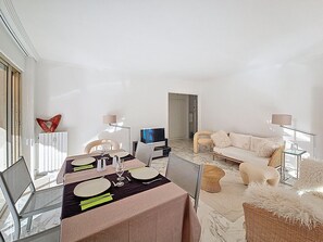 Un salon moderne avec un coin repas, des murs blancs et une grande fenêtre.