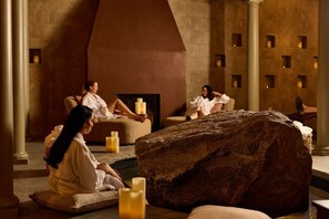 A spa setting with stone walls, a fireplace, and multiple seating areas with candles. - Mirbeau Inn & Spa Beacon (Beacon)