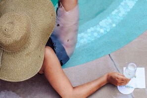 A person sitting by a pool with a drink and a napkin. - Mirbeau Inn & Spa Beacon (Beacon)