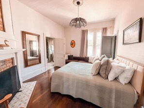 Una camera da letto con un grande letto, un camino, uno specchio e un lampadario.