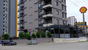 Un edificio de varios pisos con balcones, un letrero de Shell y un edificio identificado como 'Imperium Resort Konaklama'.