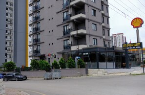 A multi-story building with balconies, a Shell gas station sign, and a building labeled 'Imperium Resort Konaklama.' - IMPERIUM RESORT HOTEL (Erdemli)
