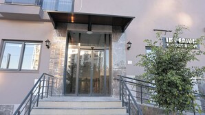 A building entrance with a glass door, metal railings, and a stone facade. - IMPERIUM RESORT HOTEL (Erdemli)
