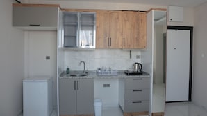 A compact kitchen with a sink, cabinets, and a refrigerator. - IMPERIUM RESORT HOTEL (Erdemli)