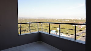 A balcony with a metal railing overlooking a cityscape with buildings and greenery. - IMPERIUM RESORT HOTEL (Erdemli)