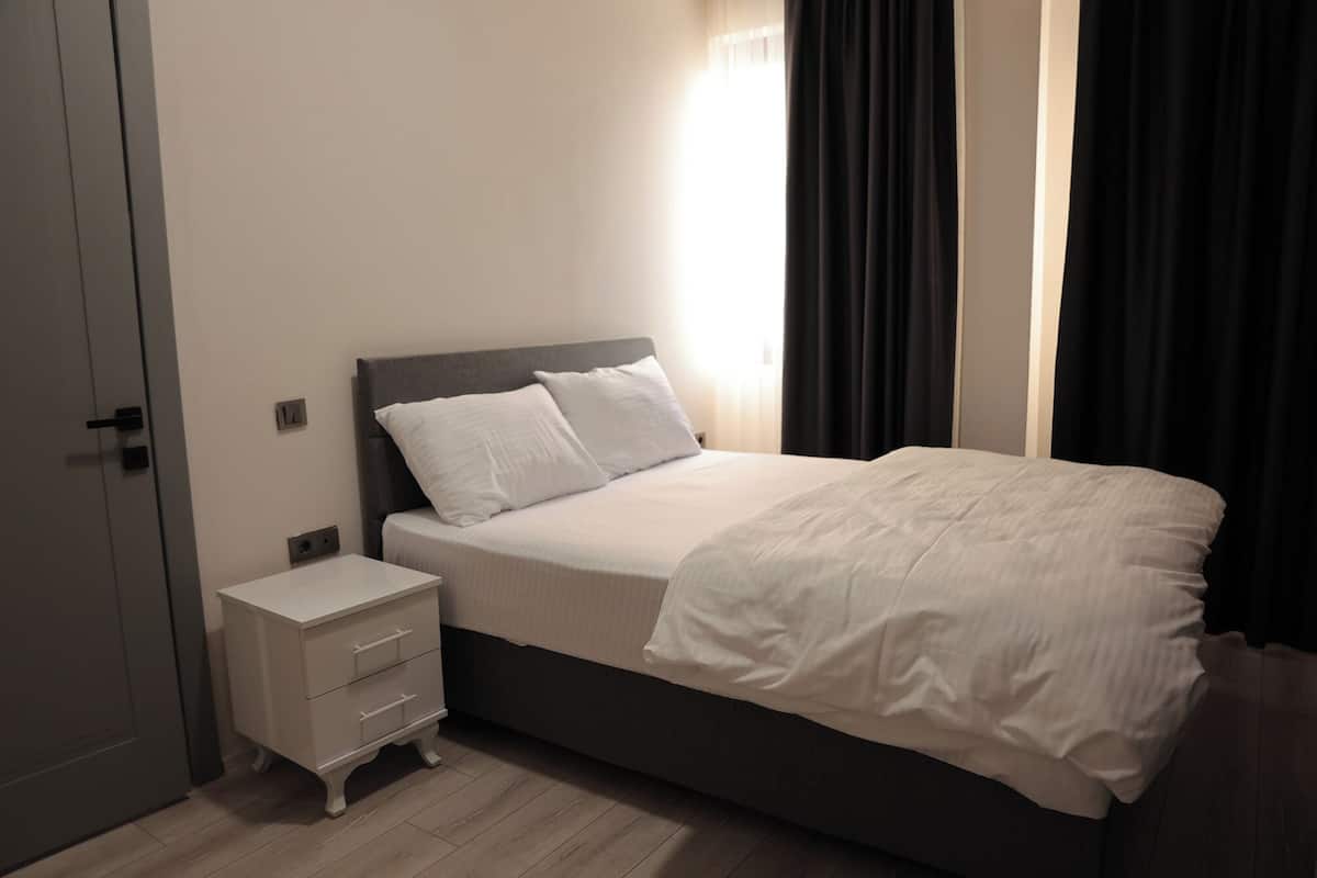 Un dormitorio con cama, mesita de noche, cómoda y puerta.