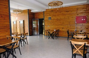 A restaurant interior with wooden walls, multiple tables and chairs, and a red cabinet. - IMPERIUM RESORT HOTEL (Erdemli)