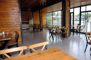 A restaurant interior with wooden walls, large windows, and multiple tables and chairs.