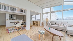 Uma sala de estar espaçosa com sofá, mesa de centro e área de refeições.