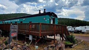 En turkis bygning med teksten "Grand Canyon", en træterrasse og et skilt, der angiver 8 kilometer i timen hastighed på indkørslen.