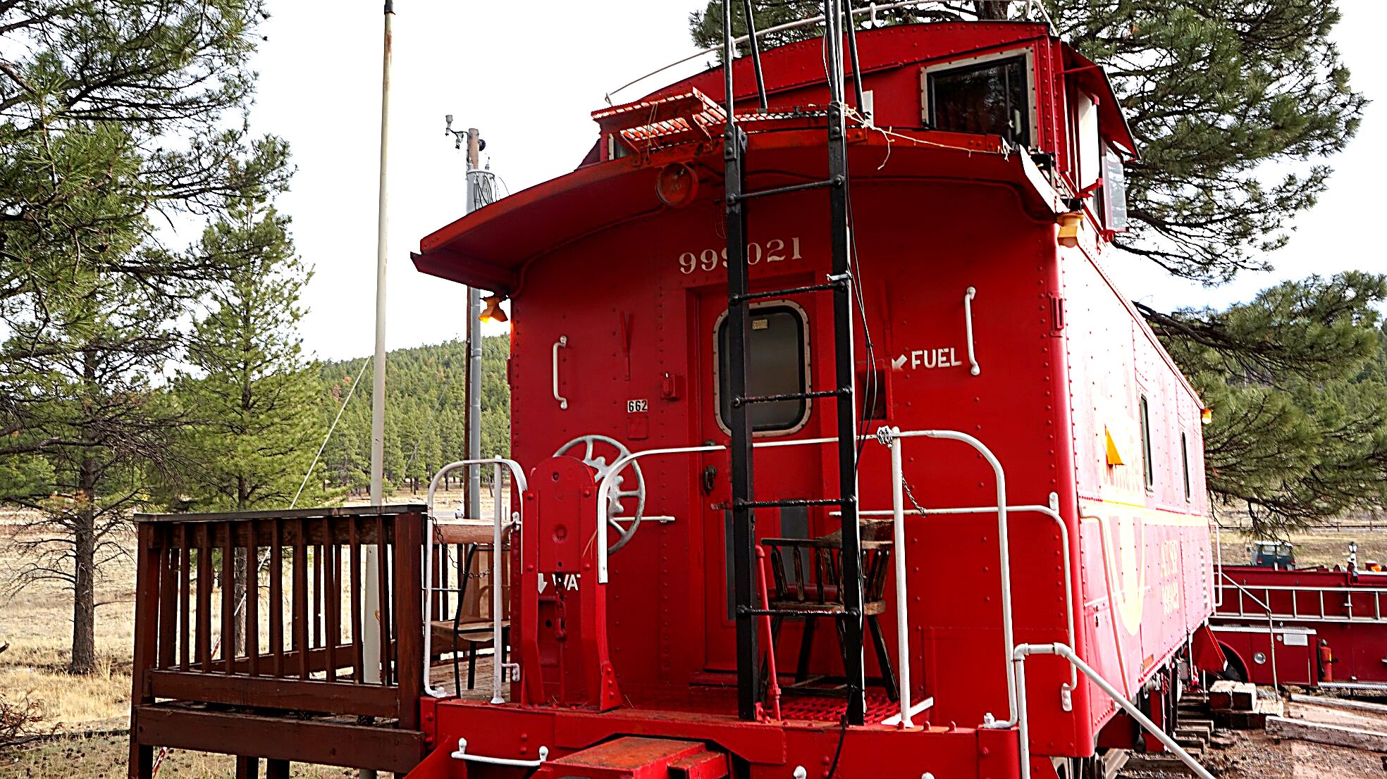 A red train caboose with the number 998 021, a small window, and a ladder.