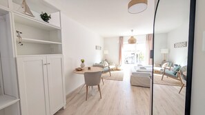 A modern living room with a dining area, a sofa set, and a small table with a vase. - Berth 1 - Modern studio apartment just 5 minutes from the beach (Timmendorfer Strand)