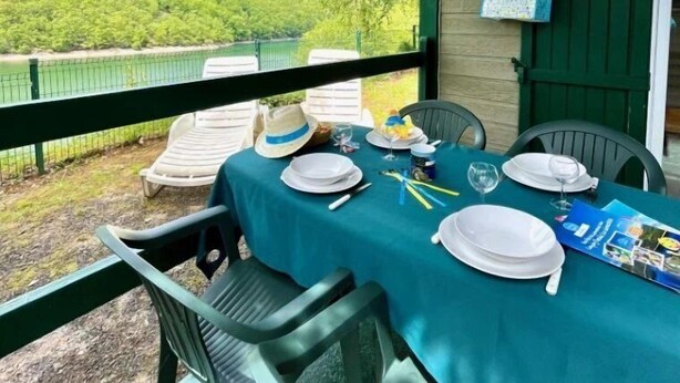 Un área de comedor al aire libre cubierta, con una mesa para dos, sillas y vistas a un paisaje verde.