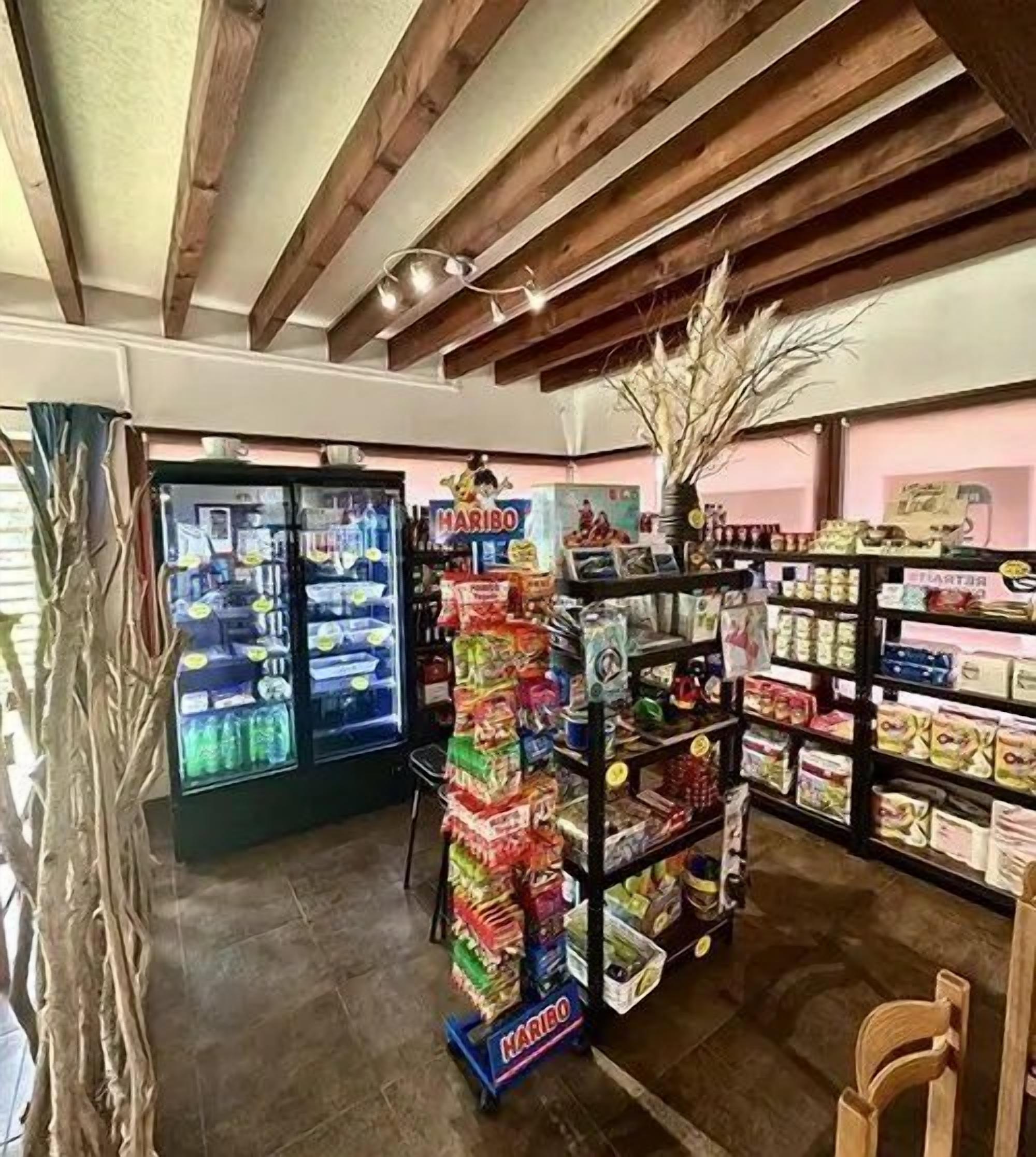 L’intérieur d’un magasin, avec un présentoir réfrigéré, une pyramide de produits d’épicerie et des étagères remplies de divers articles.