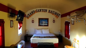 A hotel room with a bed, a television, a desk, and a chair. - Railcar on Historic Route 66 (Williams)
