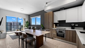 A modern kitchen with a dining area, large windows, and a view of the city.