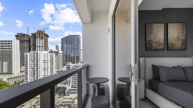 A balcony with a city view, a bed, two small tables, and a sofa.