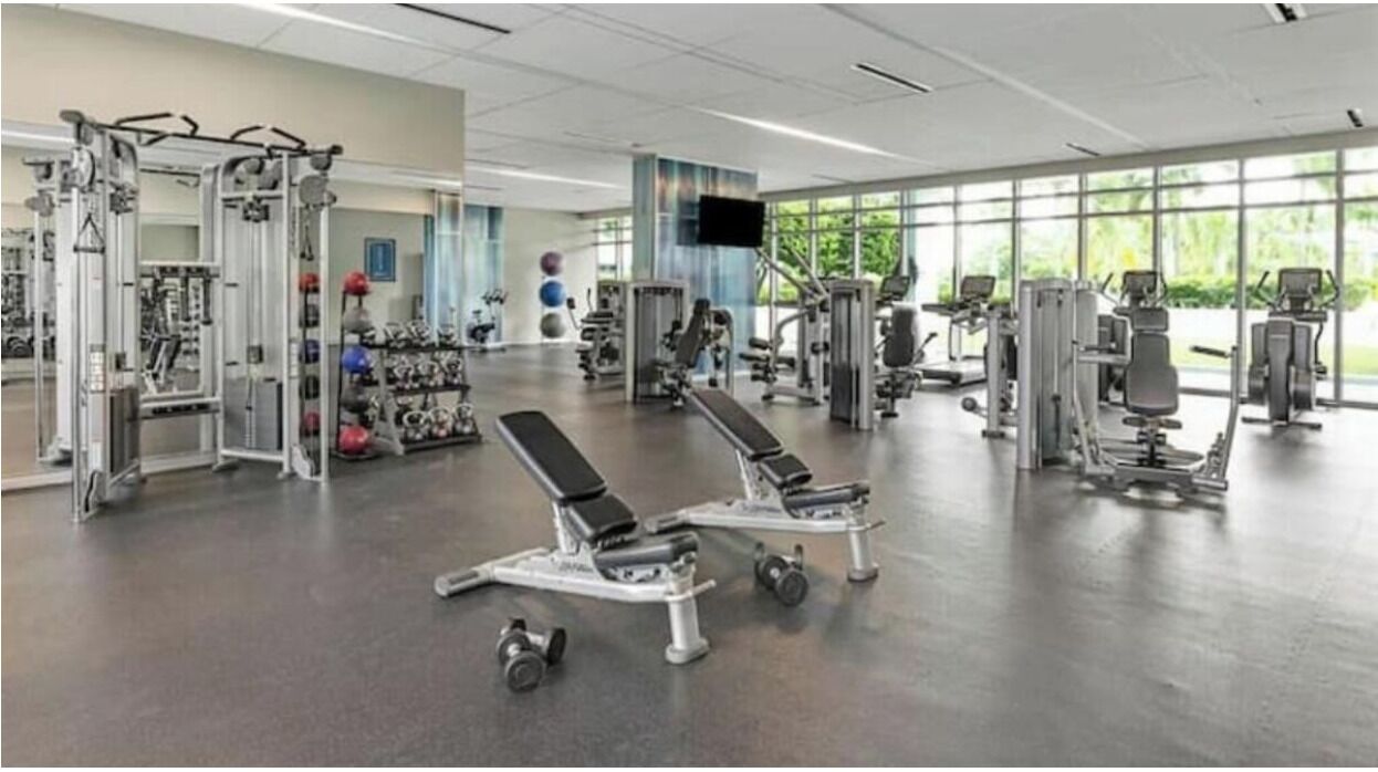 Un gimnasio con diversos equipos de ejercicio, incluyendo máquinas de pesas y aparatos cardiovasculares.