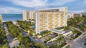 A modern hotel with multiple floors, a central courtyard, and a view of the ocean. - Luxurious 2 BRD/2BATH  Suite in serene Marco Island (Marco Island)
