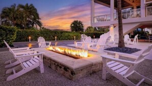 A fire pit surrounded by white Adirondack chairs in an outdoor setting with a modern building in the background. - Luxurious 2 BRD/2BATH  Suite in serene Marco Island (Marco Island)