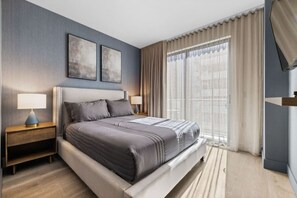 Ein modernes Hotelzimmer mit einem großen Bett, zwei Nachttischen, einer Kopfteil und einem großen Fenster mit Vorhängen.