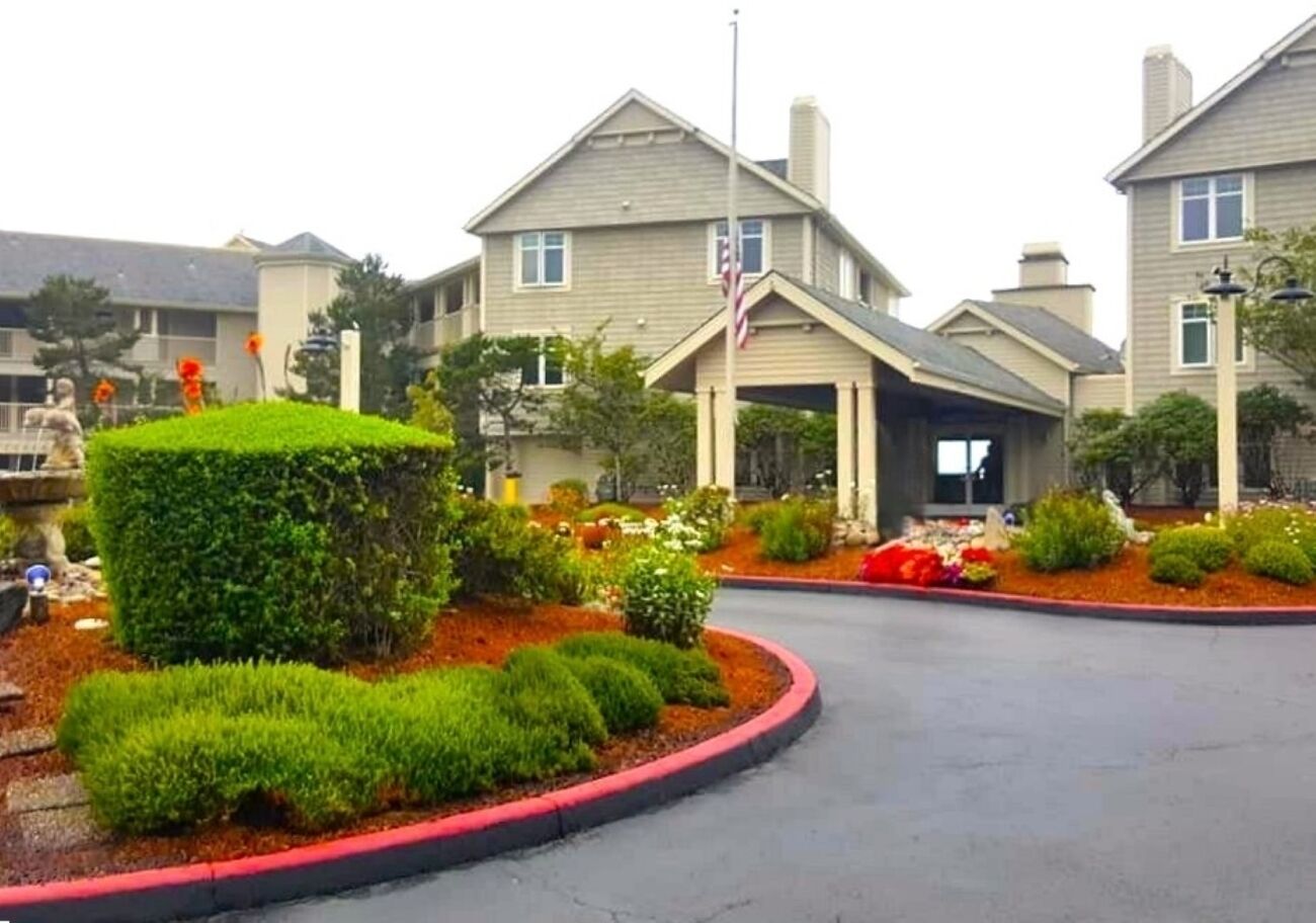 A residential building with a landscaped front yard, a driveway, and a flagpole.