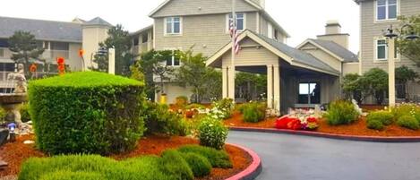 A residential building with a landscaped front yard, a driveway, and a flagpole.